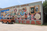An RV rental van parked before the vibrant Bertram, Texas mural, showcasing local history.