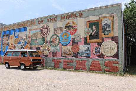 An RV rental van parked before the vibrant Bertram, Texas mural, showcasing local history.