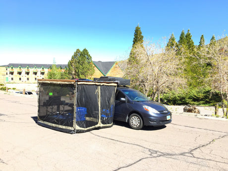 A unique RV rental experience: a minivan with an attached screen room, chairs, and table setup on pavement. Perfect for camping!