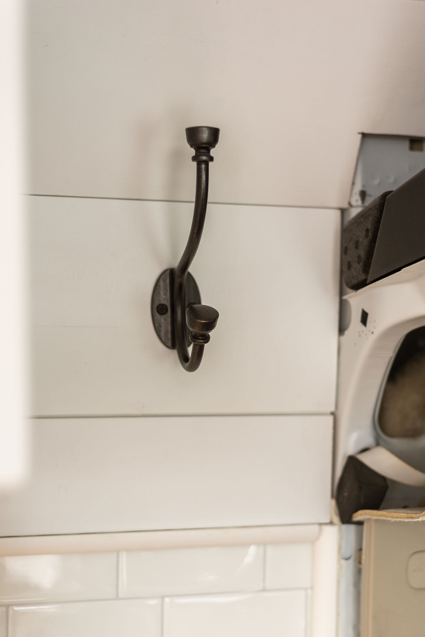 A dark metal coat hook on white shiplap wall in an RV rental, providing simple, practical storage.
