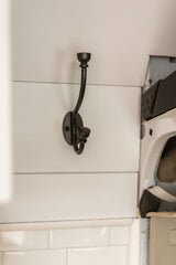 A dark metal coat hook on white shiplap wall in an RV rental, providing simple, practical storage.
