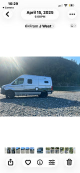Silver Winnebago Revel 4x4 rv rental parked on a rocky beach by a river with forested hills. Perfect for outdoor adventures!