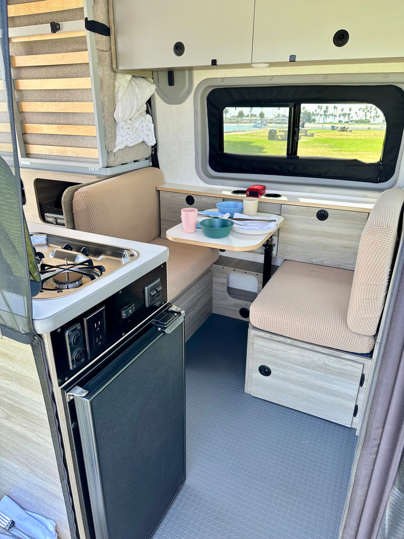 Cozy RV rental interior with compact kitchenette, dining, fridge, and a scenic window view. — photo 13