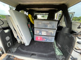 Back of a Jeep filled with camping essentials: stove, tables, & organized storage. Great for an RV rental alternative.