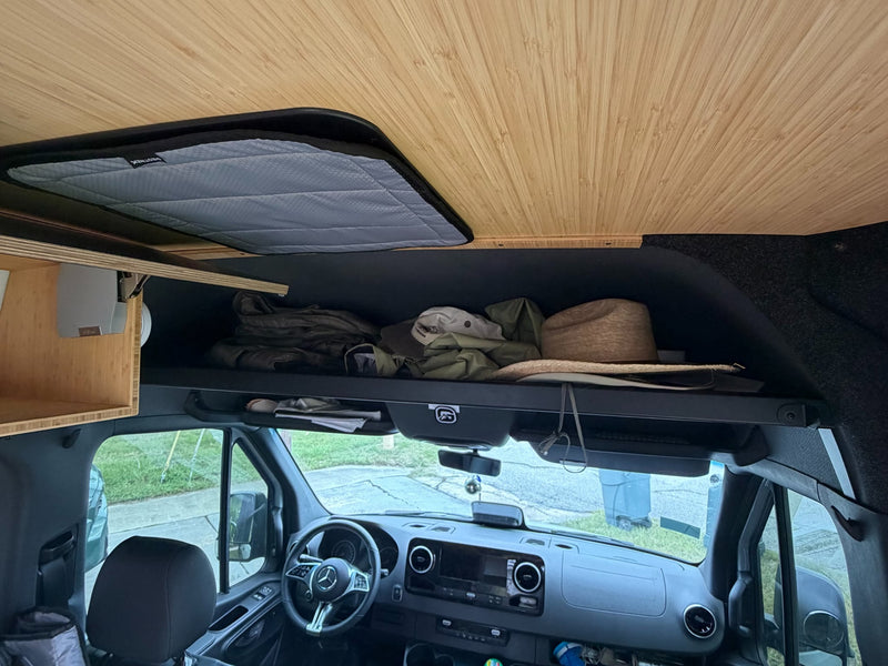  showing an open pop-out window & rear ladder. Ready for your next adventure.|RV rental camper van features an outdoor shower. Handheld showerhead and fixture on the wooden interior with open doors.|Open RV rental door reveals custom interior insulation and storage panels — photo 16
