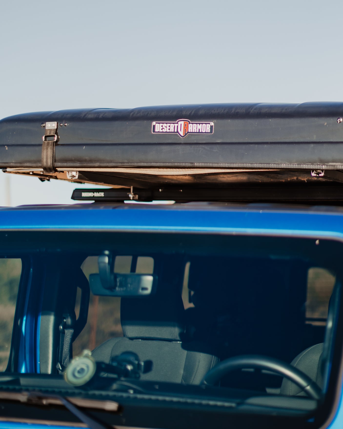 Blue vehicle with a Desert Armor roof-top tent and Rhino-Rack, ready for adventure. Ideal for an RV rental trip.