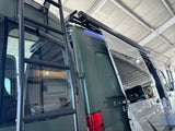 Rear of a green RV shows a roof access ladder and an awning with blue LED lights for your next rv rental.