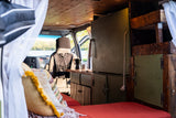Experience this RV rental: a cozy camper van conversion with kitchen, bed, and scenic lake view.