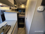 Cozy RV rental interior: equipped with a compact kitchen, microwave, comfortable bed, and safety features.