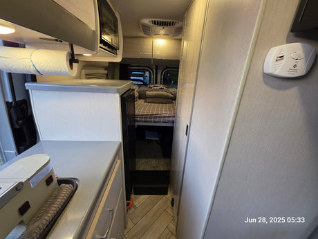 Cozy RV rental interior: equipped with a compact kitchen, microwave, comfortable bed, and safety features.