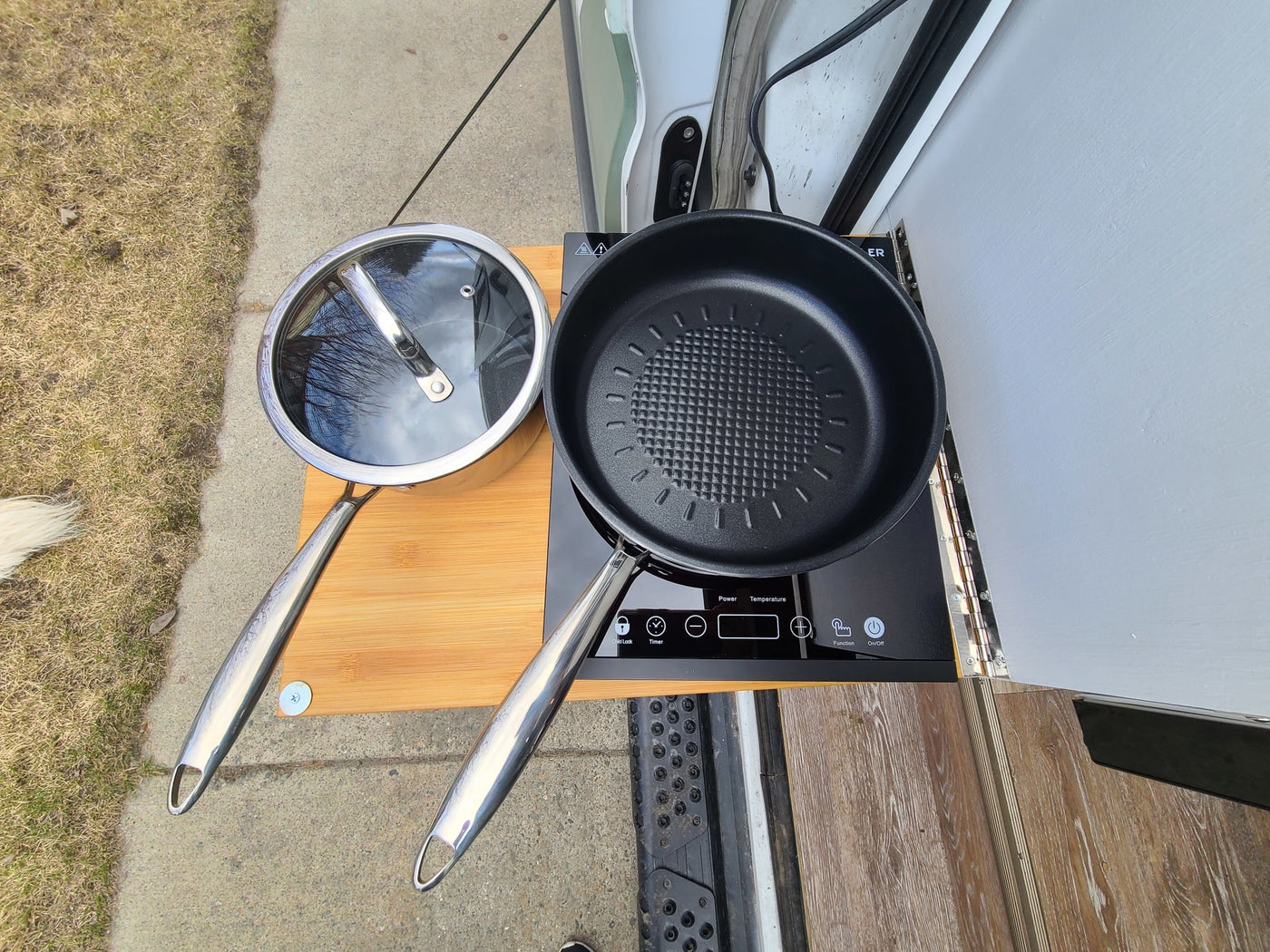 An RV rental's portable outdoor kitchen: an induction cooktop with a pan and pot sits on a bamboo board near the door. — photo 12
