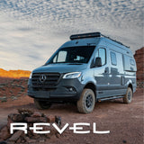 Grey Winnebago Revel camper van for rv rental, parked on an off-road trail with red rock landscapes under a cloudy sky.