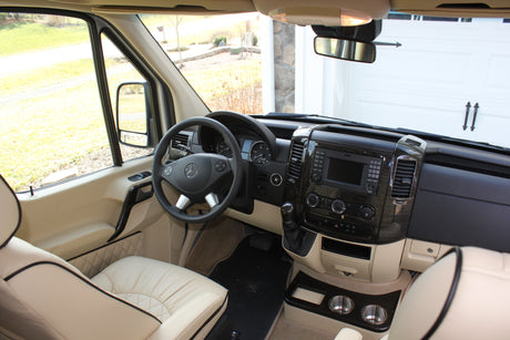 Spacious RV rental interior: driver's perspective with light-colored seats, steering wheel, and modern dashboard.