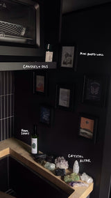 Cozy dark interior of an RV rental: microwave, mini photo wall, and crystal altar on a wooden counter. Personalized compact space.