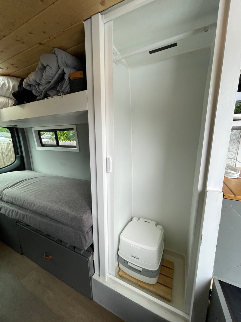 Experience an RV rental's clever interior: a comfortable bed, upper bunk, and a private area with a portable toilet. — photo 19