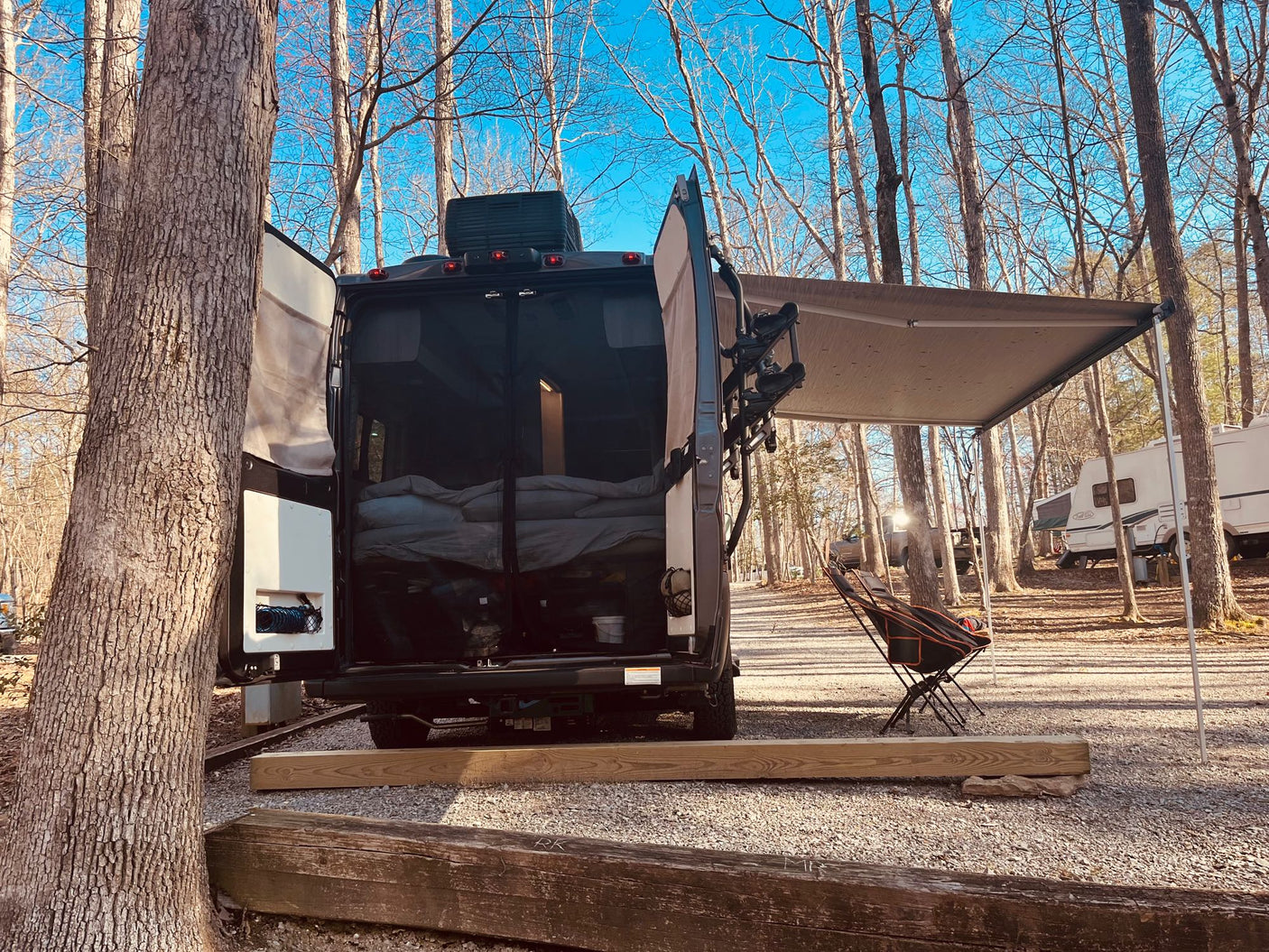 Enjoying the outdoors in an RV rental! This camper van is set up for a cozy stay at a sunny campground.