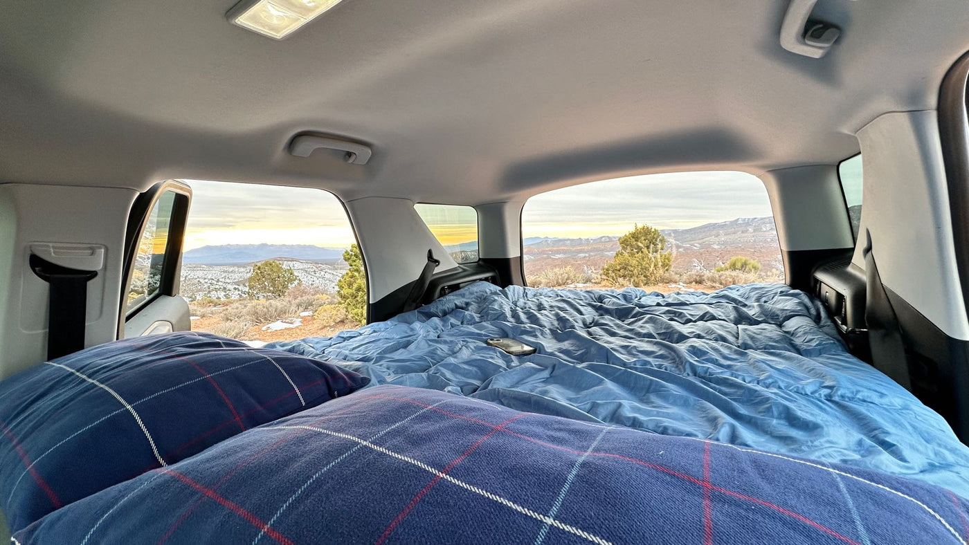  like an RV rental experience.|Interior of a parked vehicle with a cozy bed. Outside — photo 9
