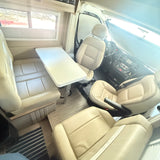 Interior of an RV rental showing cream seating, a central table, and the driver's area with dashboard. A comfortable travel space.