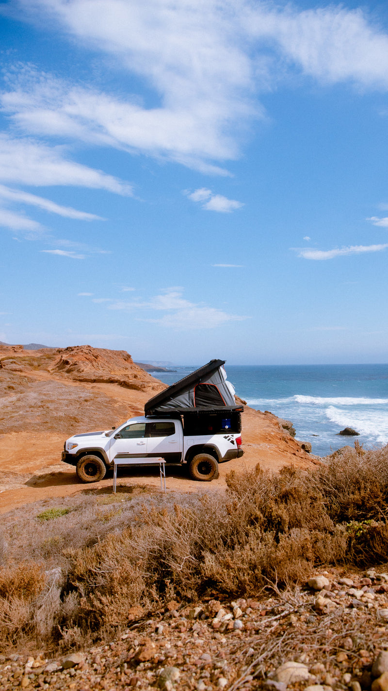 Coastal camping: White pickup truck with deployed pop-up camper on a cliff overlooking the ocean. RV rental ready! — photo 2