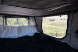 Relaxing RV rental interior: cozy bed, open windows, and a scenic outdoor view for your next adventure.