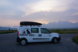 White campervan with roof box, parked on road. Grand Teton mountains and colorful sky. Ideal RV rental for scenic adventures.