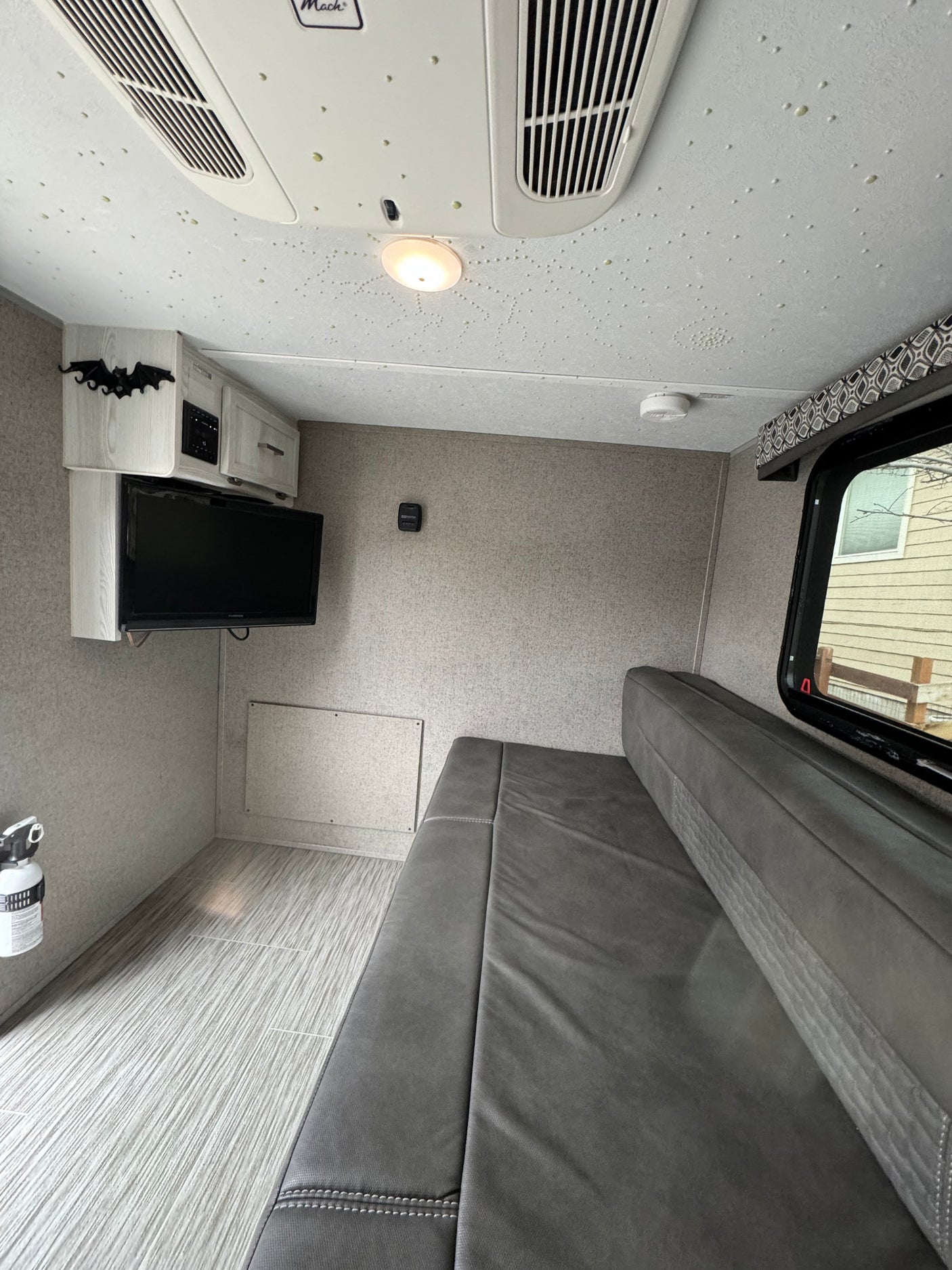 RV rental interior: cozy seating, mounted TV, AC, and playful glow-in-the-dark ceiling dots.