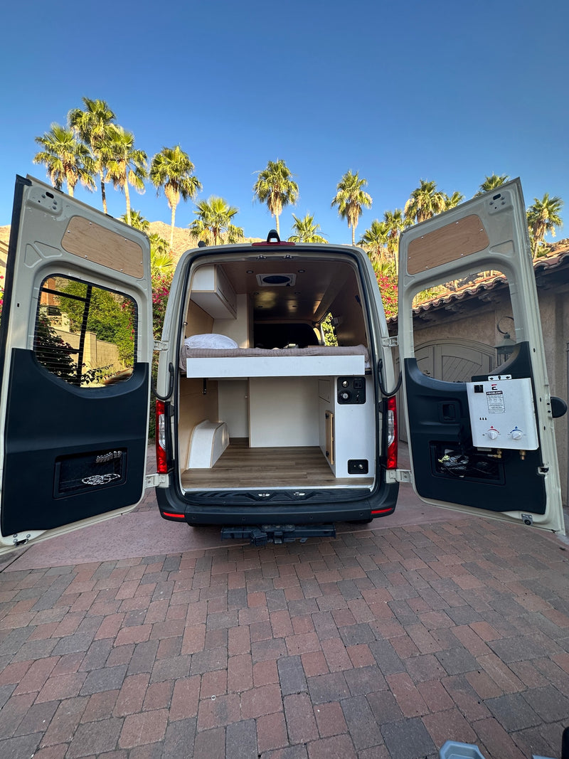Spacious custom camper van conversion with open rear doors, ready for adventure. Ideal for rv rental, featuring a bed & amenities under palm trees. — photo 18