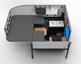 Aerial view of a modern RV rental interior, featuring modular bed/seating, a portable fridge, and a functional table.