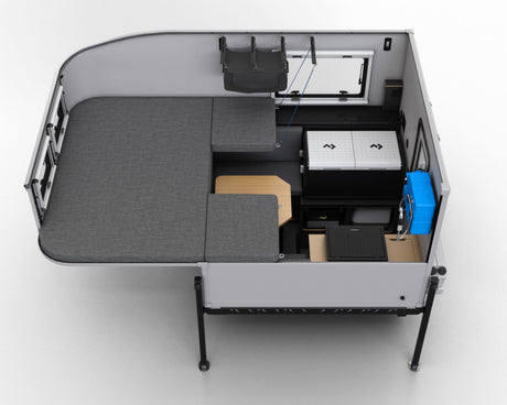 Aerial view of a modern RV rental interior, featuring modular bed/seating, a portable fridge, and a functional table.