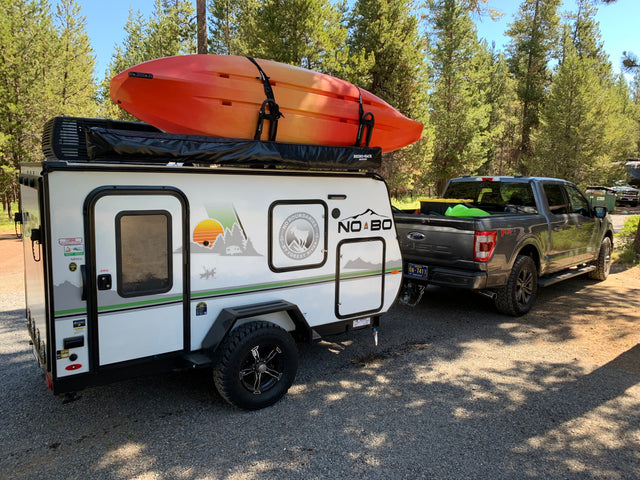 RV rental adventure: A No Boundaries travel trailer with a kayak is hitched to a Ford F-150, ready for outdoor fun.