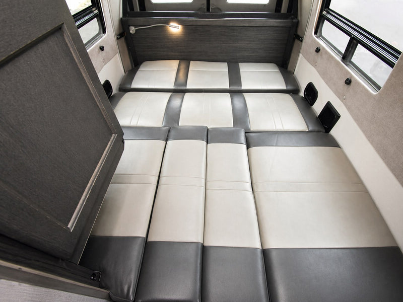 Spacious RV rental interior featuring a comfortable convertible bed with two-tone grey and off-white cushions, ideal for travel. — photo 5
