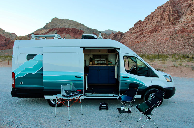 White RV rental camper van parked in the desert with open kitchen, outdoor stove & chairs setup. — photo 6
