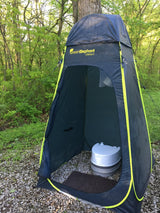 GreenElephant privacy tent with portable toilet on gravel, surrounded by trees. Ideal for your RV rental adventures.