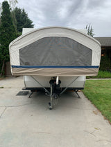 Front of a tan pop-up camper RV rental with a mesh window, parked on a driveway, ready for adventure.