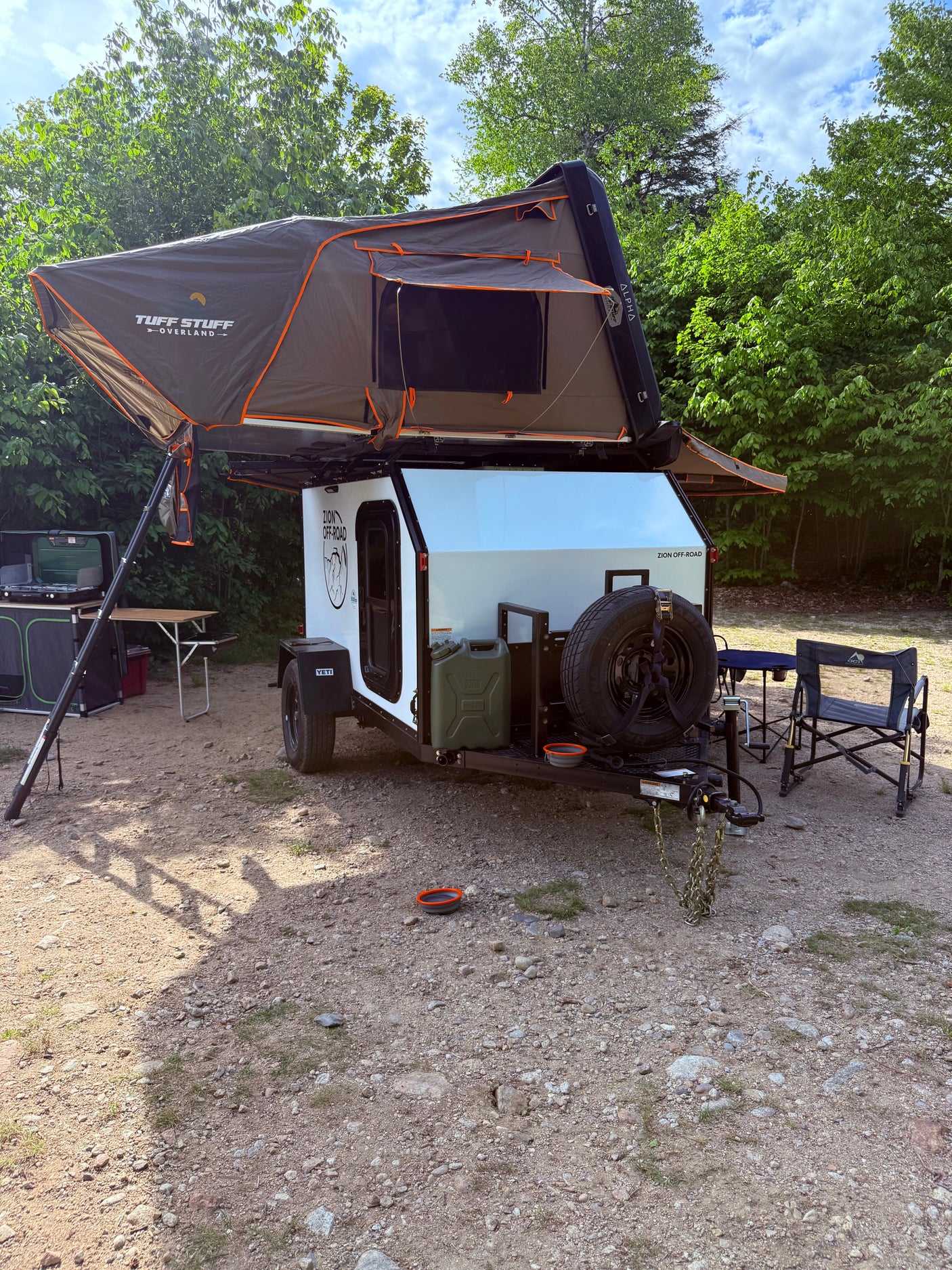 Overland **RV rental**: Tuff Stuff rooftop tent on a Zion Off-Road camper trailer, with an outdoor kitchen setup & chairs.