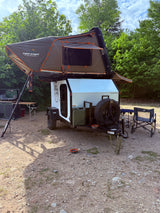 Overland **RV rental**: Tuff Stuff rooftop tent on a Zion Off-Road camper trailer, with an outdoor kitchen setup & chairs.