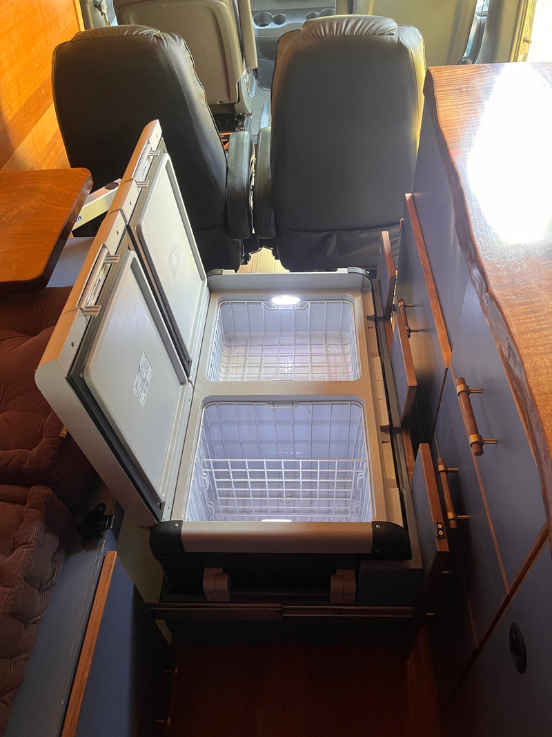 Functional RV rental interior: clear view of the open, dual-zone refrigerator/freezer and pull-out prep surfaces. — photo 4