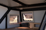 Interior of an RV rental: well-appointed space with large windows, power hub, and comfy sleeping area.