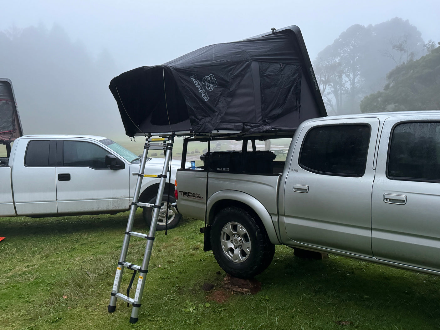 Truck with iKamper rooftop tent, ladder in foggy campsite. Great for outdoor camping & an RV rental option.