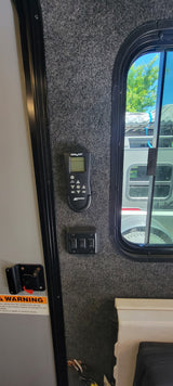 RV rental interior: MaxxAir fan remote, control switches, and a window for exterior views. Essential RV controls.