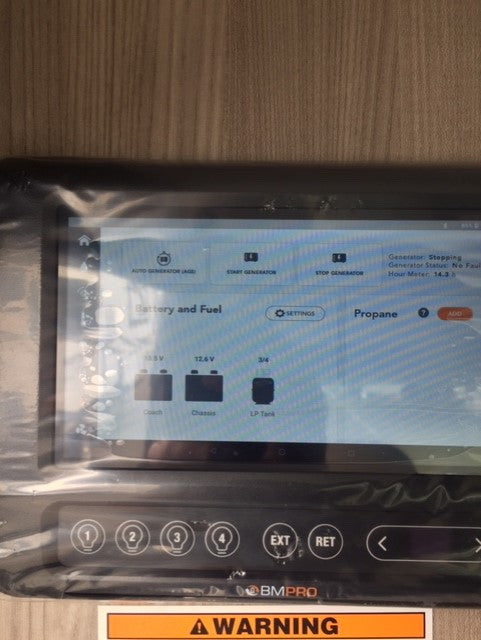 RV rental digital control panel (BMPRO) displaying battery levels, LP tank, & generator status with physical buttons below.