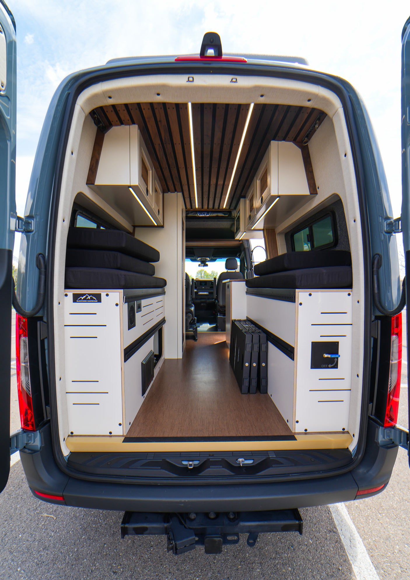 Step inside this custom camper van for your next RV rental! Features a modern wood-slat ceiling, modular storage & beds.