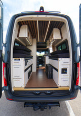 Step inside this custom camper van for your next RV rental! Features a modern wood-slat ceiling, modular storage & beds.