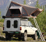 Truck camping RV rental: A white 4WD pickup with a Rooftnest rooftop tent and ladder, ideal for mountain adventures.