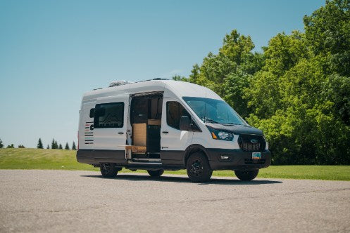 White Ford Transit van RV rental, side door open, showcasing its spacious campervan interior. Ready for adventure!