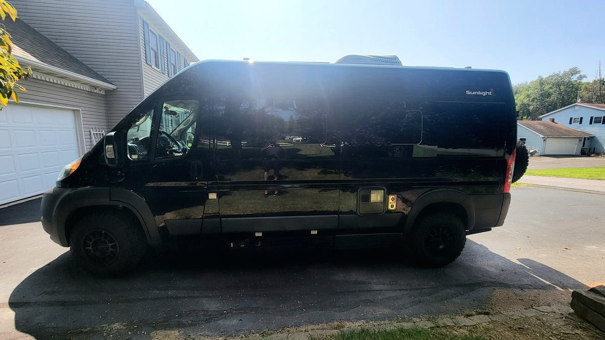 Profile view of a sleek black Sunlight camper van, parked on a driveway for an RV rental. — photo 5