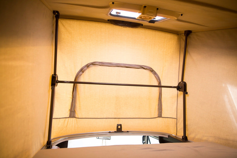 View inside an RV rental pop-top camper, featuring light fabric walls, support poles, a zippered opening, and overhead vent. — photo 9