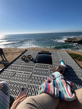 Relaxing on an RV rental rooftop deck overlooking the scenic coast. Blue skies, ocean waves, and flying birds.