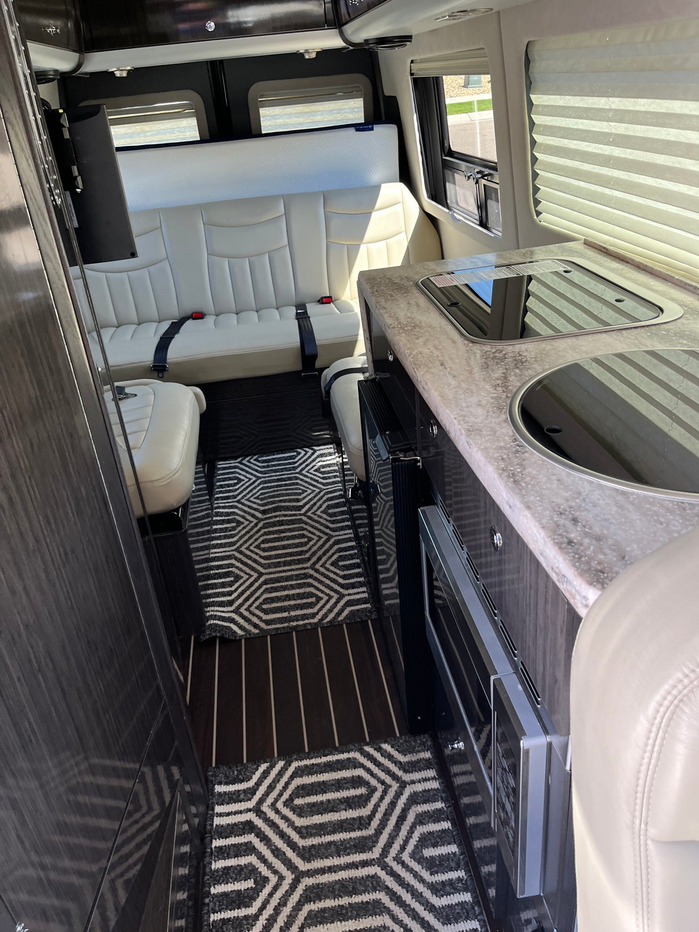 Spacious RV rental interior with light leather seating, a modern kitchen counter, and integrated appliances, ideal for travel.