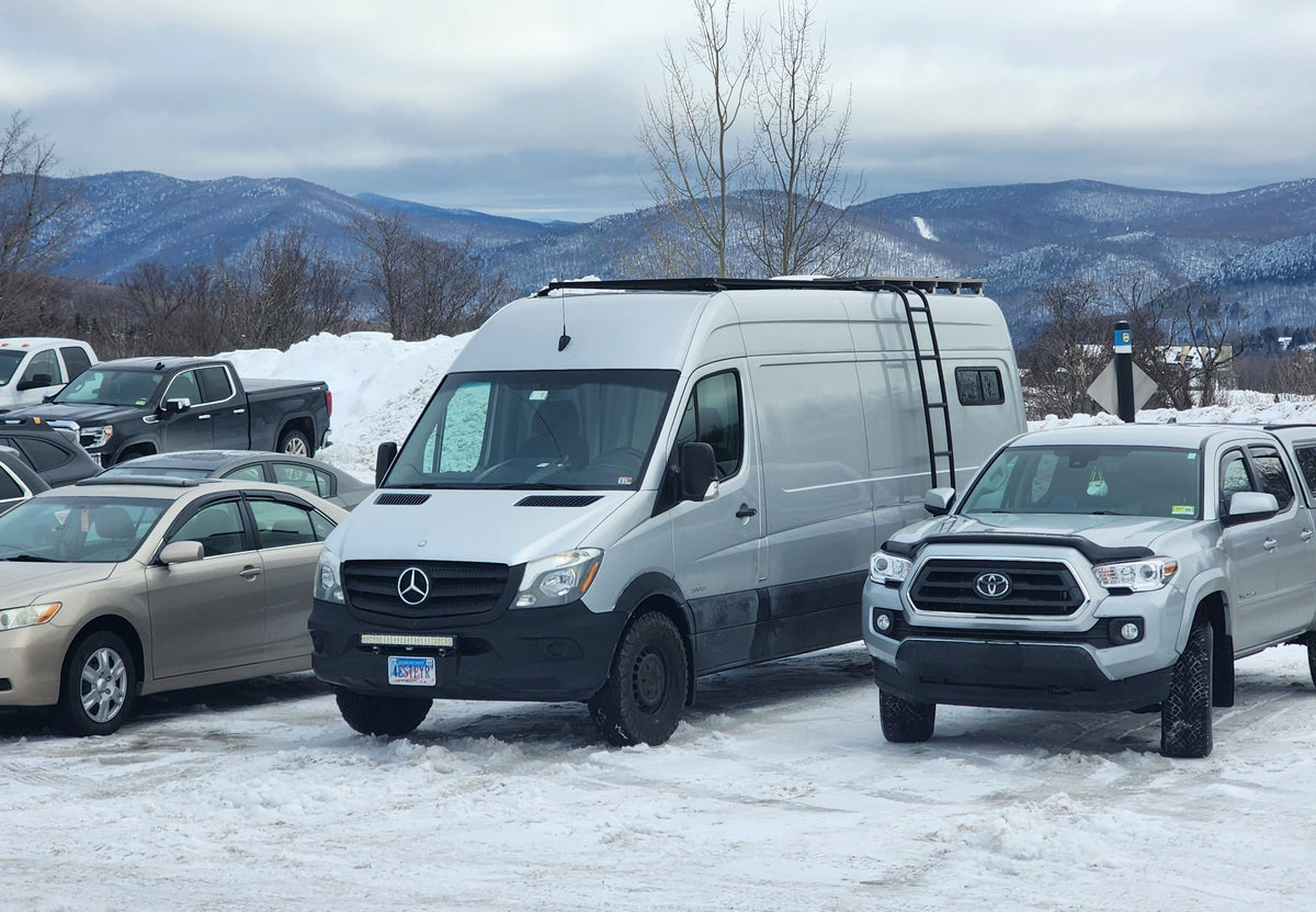 A silver Mercedes Sprinter van, ready for adventure (an RV rental option), parked among other vehicles in a snowy mountain lot. — photo 12
